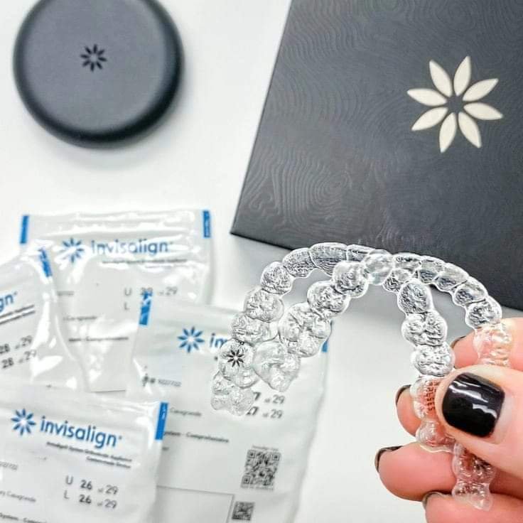 Alineadores transparentes junto a sus estuches y envases Invisalign.